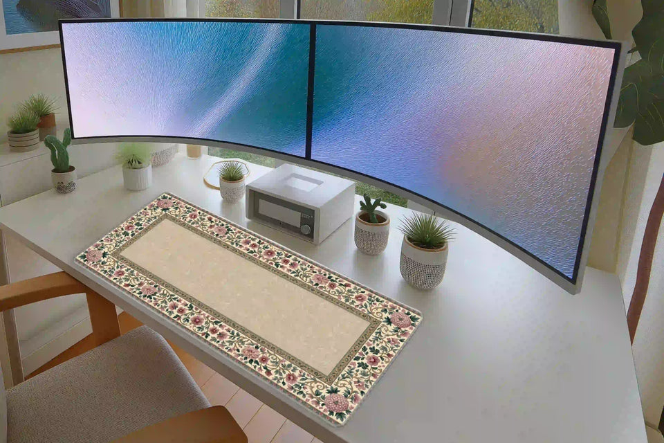 Vintage floral border desk mat on a white desk beneath two monitors, with its cream center and pink blossoms visible