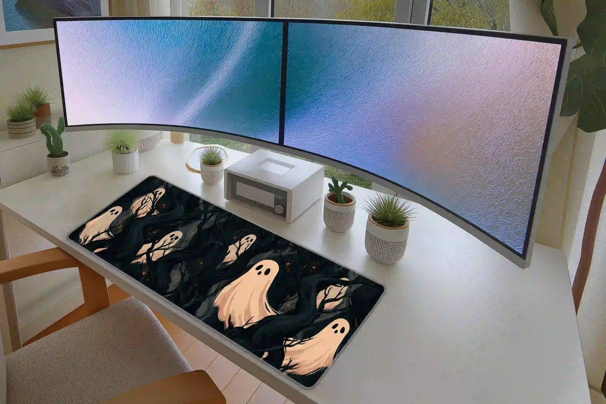 Haunted ghost forest desk mat across a white desk beneath dual monitors, with the full woodland print visible