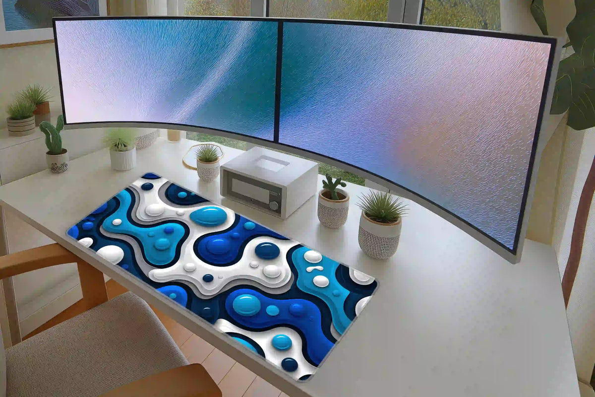 Blue liquid bubble desk mat on a white desk below two monitors, showing blue and white layered abstract artwork