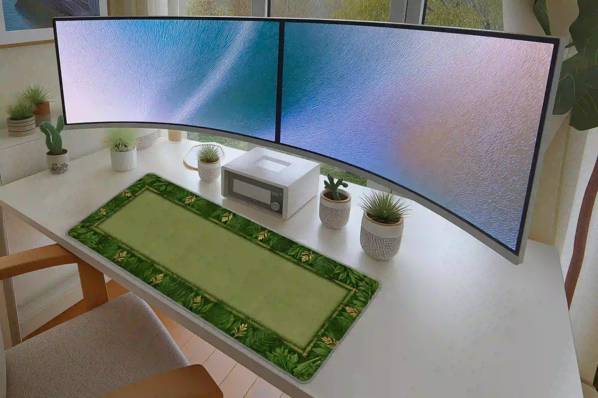 Green leaf border desk mat on a white desk with potted plants and dual monitors, showing its open center