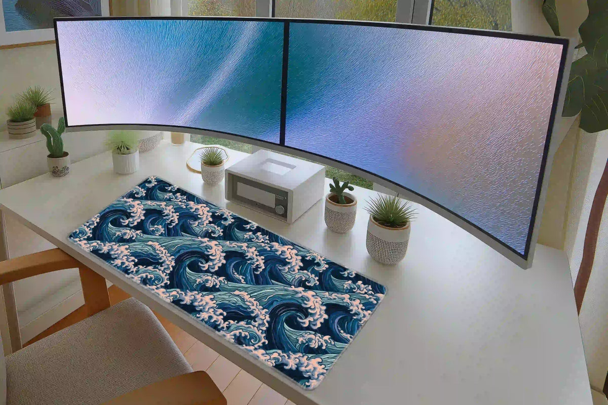 Japanese-inspired blue wave desk mat arranged across a white desk below dual monitors and potted plants