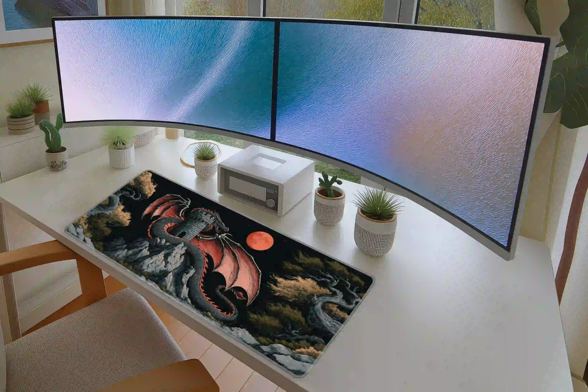 Red moon dragon desk mat in a dual-monitor setup, with red wings spread around a stone tower in the dark artwork