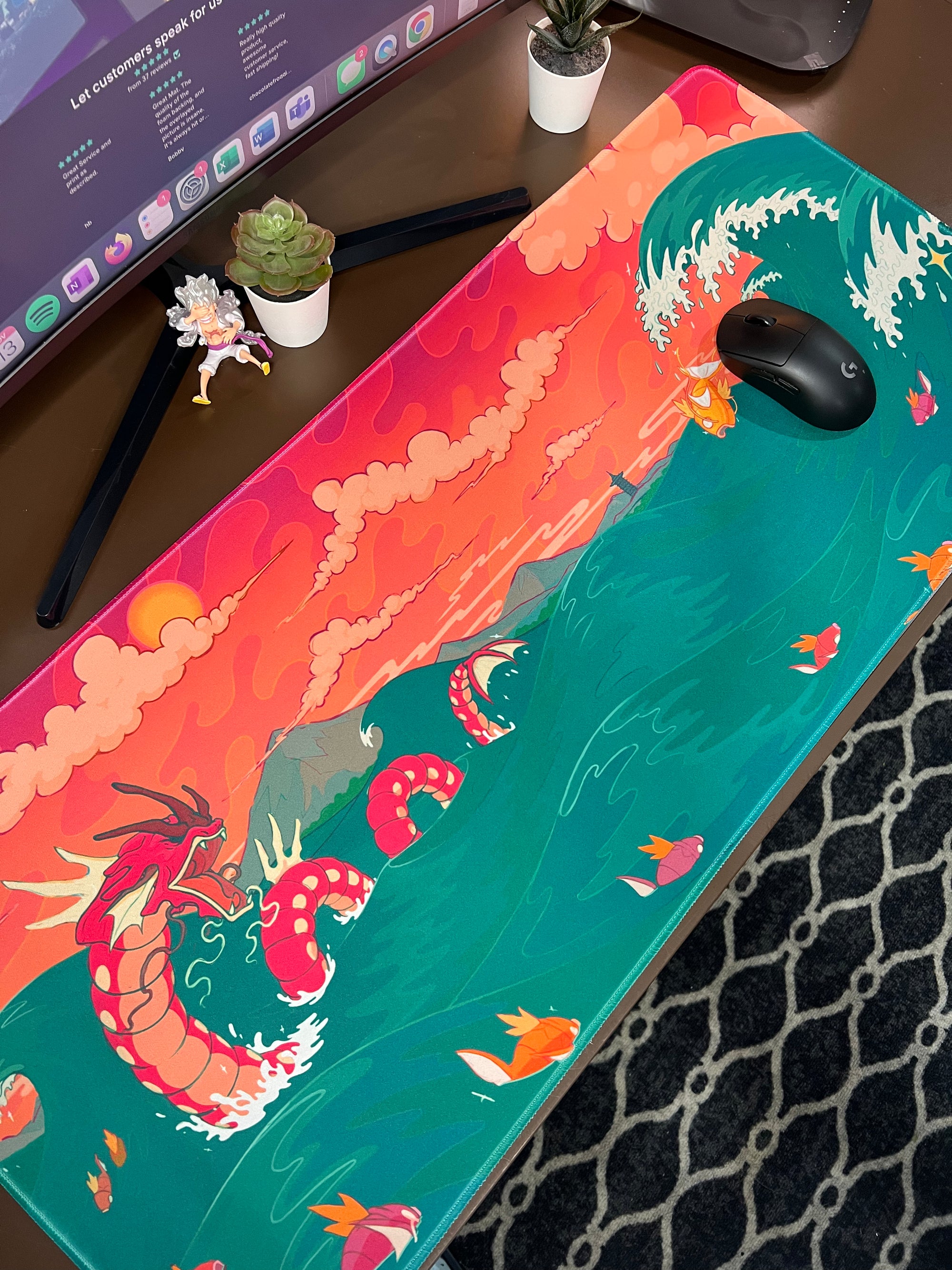 Custom mouse pad printed with a red sea dragon and koi fish in turquoise waves beneath an orange sunset, shown on a computer desk.