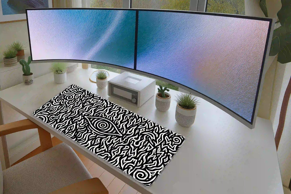 Hypnotic eye desk mat on a white desk under curved monitors, showing bold black and white optical linework