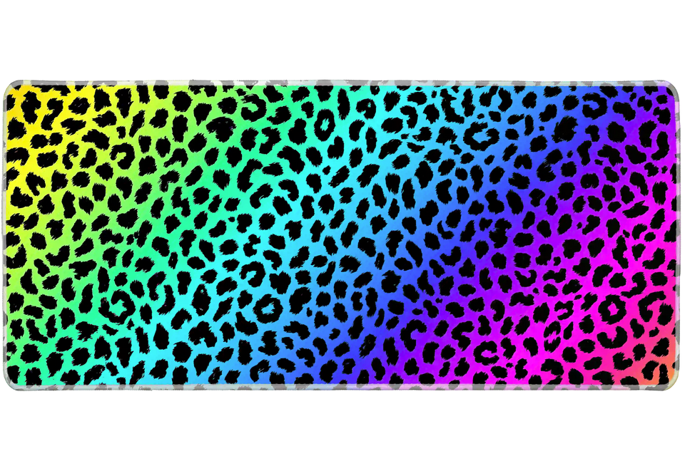 Full-width Rainbow Leopard desk mat showing black leopard spots over a vivid rainbow gradient