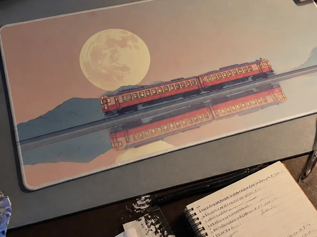 A creator workspace featuring a custom illustrated train desk mat